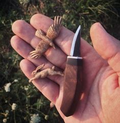 a small bird figurine sitting on top of a knife in someone's hand