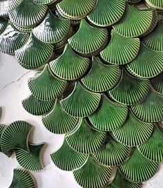 many green plates are arranged on the table top, and one is made out of leaves