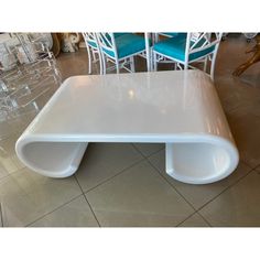 a white coffee table with blue chairs in front of it on tiled floored area