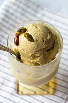 a scoop of ice cream with pistachio and cashews on top in a glass bowl