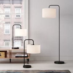 three floor lamps sitting on top of a rug next to a window