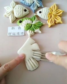 a person is holding a fork and pointing at some fake fish on a table with chinese writing