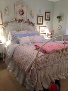 a white bed sitting in a bedroom next to a wall with pictures hanging on it