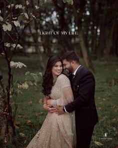 a man and woman standing next to each other in front of trees with the words light of my life written on it