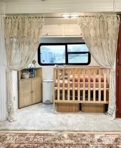 the interior of a recreational vehicle with curtains and crib in front of it on carpeted flooring