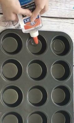 a person is dipping something into a cupcake pan with muffin tins in it