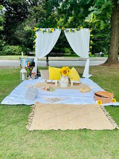 a picnic table with sunflowers and other items on it in front of a tree