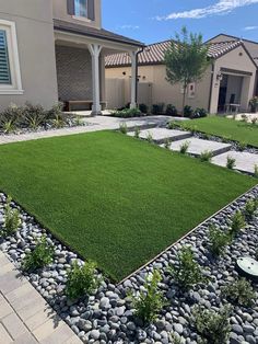 a lawn with rocks and grass in front of a house