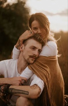 a man holding a woman on his back while she is wrapped up in a blanket