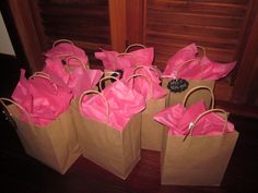 four brown paper bags with pink bows on them