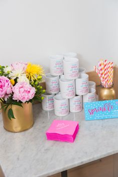 a table topped with lots of pink and yellow flowers on top of a white counter