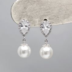 * Genuine Swarovski Elements® 10mm White Round Pearls * Available in Silver Plated, Gold Plated, Or RoseGold Plated * Teardrop CZs Stud Earrings with .925 Sterling Silver Ear Post * Length : Approx 2.7 cm / Width 1 cm * High quality premium material from US vendors. * Handmade item This gorgeous Swarovski crystal White pearl earrings are made to order to fulfill the high quality. If you have any questions about this Earrings, please let us know! We are happy to assist you. Classic Teardrop Bridal Earrings For Mother Of The Bride, Classic Crystal Bridal Earrings As Gift, White Pearl Earrings, Wedding Bridesmaid Jewelry, Pearl Earrings Wedding, White Pearl Earring, Jewelry Bridesmaid, Winter Formal, Crystal White