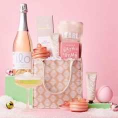 a pink and white bag filled with personal care items next to a bottle of wine