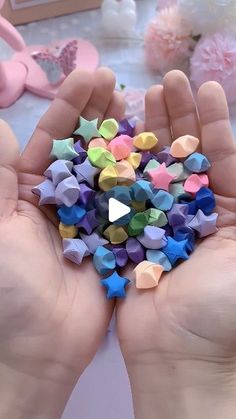 two hands holding small colorful origami stars