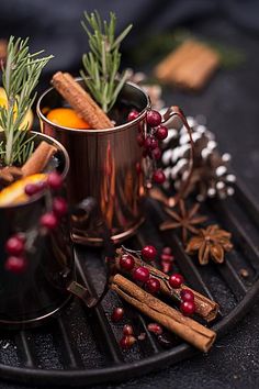 two mugs filled with different types of food on top of a metal tray next to cinnamon sticks