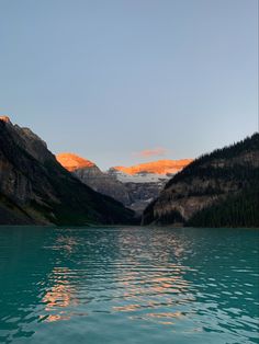 the mountains are reflected in the still water of this mountain lake at sunset or sunrise