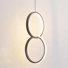 a circular light hanging from the ceiling in front of a white wall with an eight sign on it