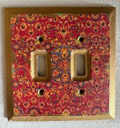 two light switch plates on a red and gold wall