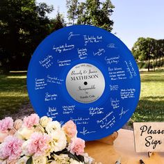 a blue plate sitting on top of a table covered in writing and flowers next to a sign