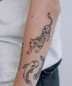 a woman with a tiger and fish tattoo on her arm is looking at the camera