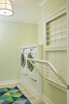 a washer and dryer in a small room with green wallpaper on the walls