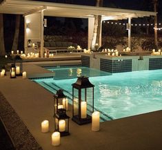 an outdoor pool with lit candles around it