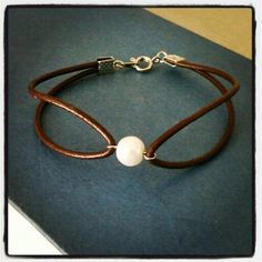 a brown leather bracelet with a white pearl