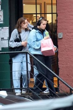 two girls are walking down the stairs carrying shopping bags