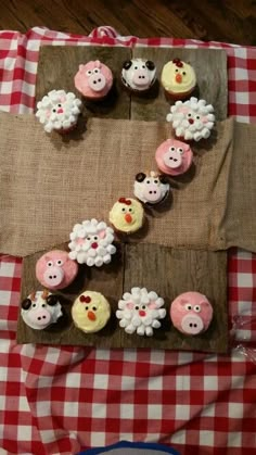 cupcakes are arranged in the shape of sheep and pigs on a tablecloth