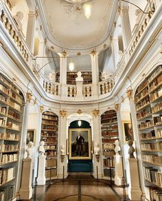 the inside of a large library with many bookshelves and sculptures on either side