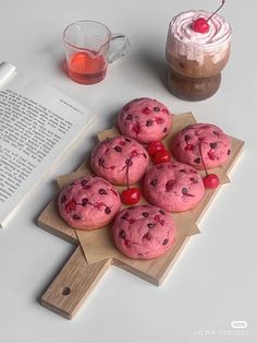 there are cookies with cherries on the table next to an open book