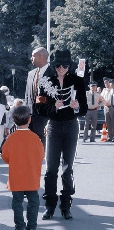 a woman walking down the street with a small child in front of her and an older man standing next to her