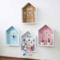 three little houses are hanging on the wall with key hooks and keys attached to them