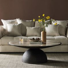 a living room with a couch, coffee table and yellow flowers in the centerpiece