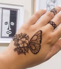 a woman's hand with a butterfly tattoo on her left wrist and flowers in the middle