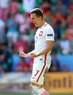 a male soccer player in action on the field with his mouth open and hands out