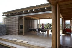 a woman sitting at a table on top of a wooden deck next to a wall