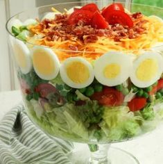 a salad with hard boiled eggs, tomatoes and lettuce in it on a table