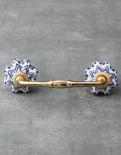 a pair of blue and white flower shaped hair pins on a gray surface with gold accents