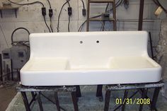 a white sink sitting on top of a metal stand in a room filled with wires