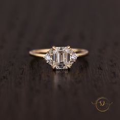 an emerald cut diamond ring on a wooden table