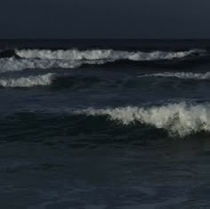 a man riding a wave on top of a surfboard in the ocean at night