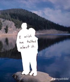 a man standing on top of a rock next to a lake