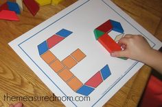 a child is playing with colored shapes on the paper that they are holding in their hands