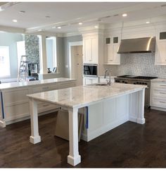 a large kitchen with white cabinets and marble counter tops, along with an island in the middle