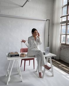 a woman sitting on a chair in front of a white wall