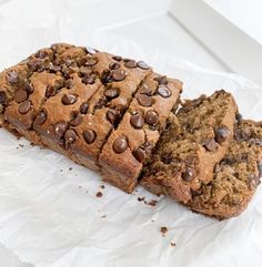 two slices of chocolate chip banana bread on top of white paper with crinkled edges