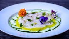 a white plate topped with cucumber and flowers on top of it's side