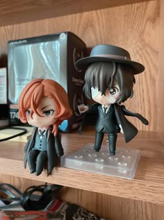 two anime figurines are sitting on a shelf