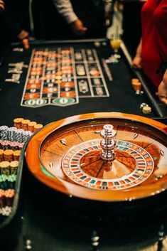 a casino rouleet table with people standing around it